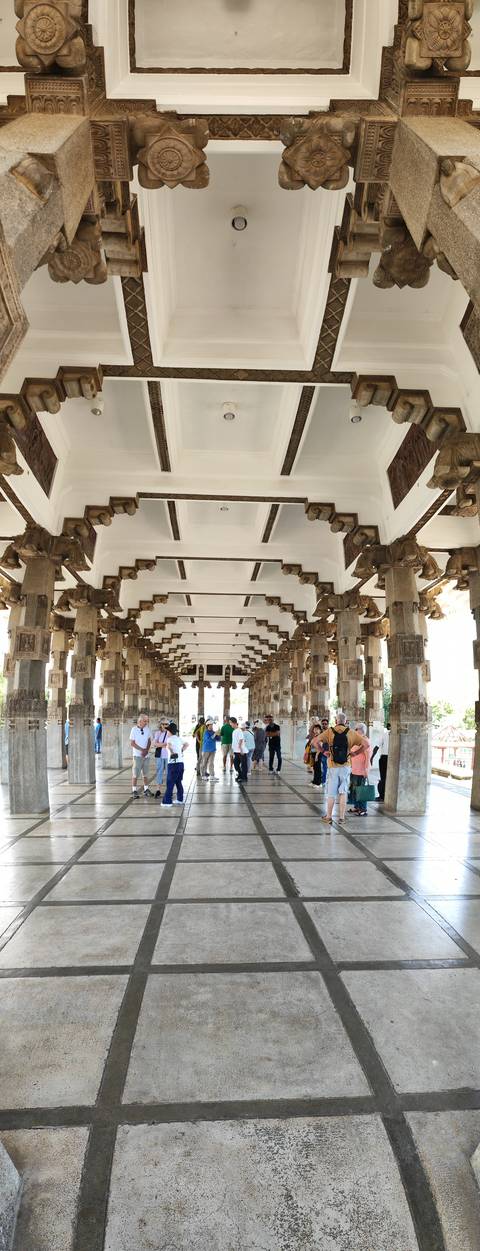       Interior of a grand pillared hall filled with tourists touring the historic monument.
  