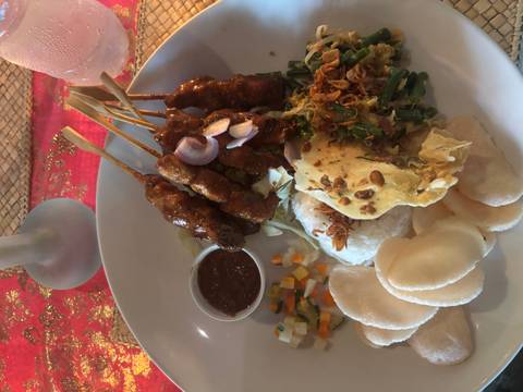       Indonesian meal with chicken satay skewers, rice, vegetables and peanut sauce served in a bowl
  