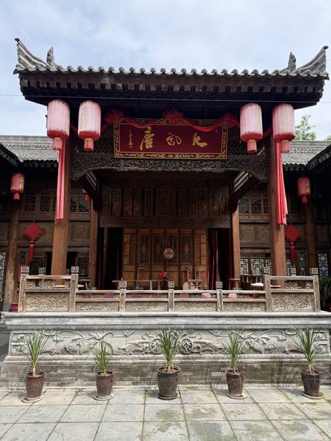       Elaborately carved wooden stage façade with red lanterns and Chinese characters, representing classical architecture.
  