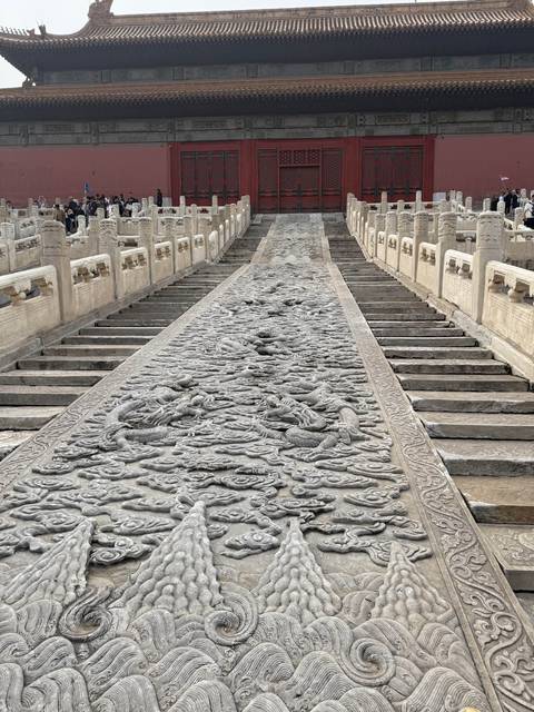      Long stone ramp intricately carved with dragons and clouds, flanked by marble staircases in an imperial courtyard.
  