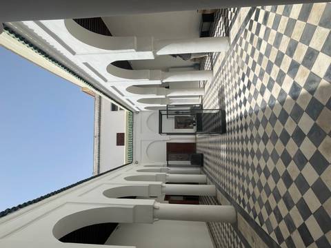      Bright interior courtyard with white arches, chequered floor tiles and display cases.
  
