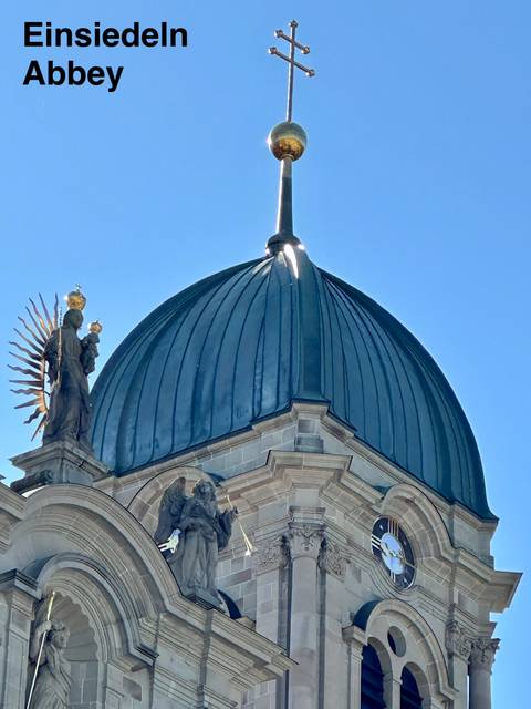       Close-up of a blue domed church roof with a statue against a clear sky.
  