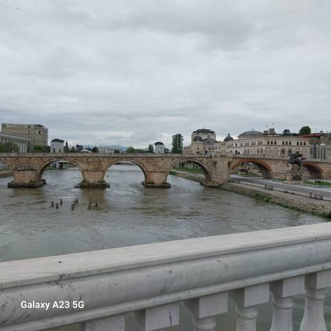       Historic multi-arch stone bridge crossing a wide river with Ottoman-style buildings beyond.
  