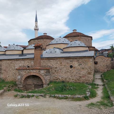       Historic stone hammam complex with multiple lead-covered domes and a tall brick chimney.
  