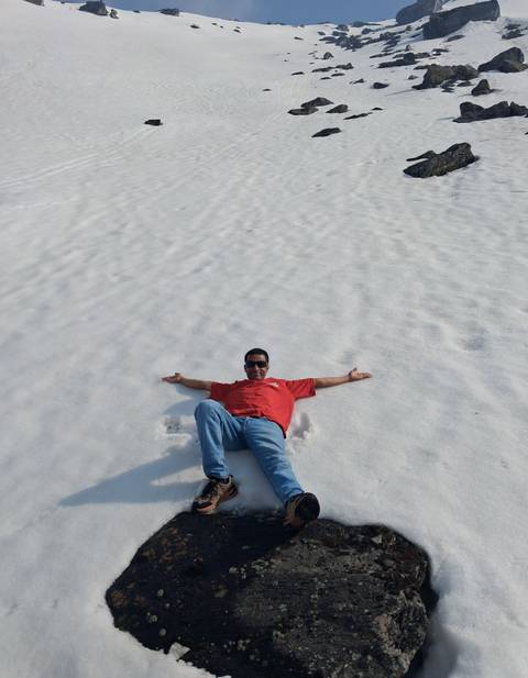       Man in red shirt reclines happily on a wide field of snow stretching to the horizon.
  