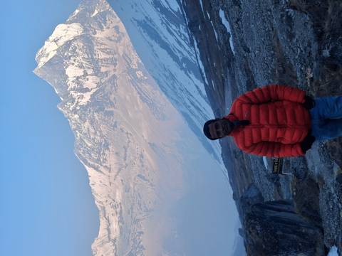       Same traveller poses against rugged Himalayan peaks with early light highlighting snowy ridges.
  