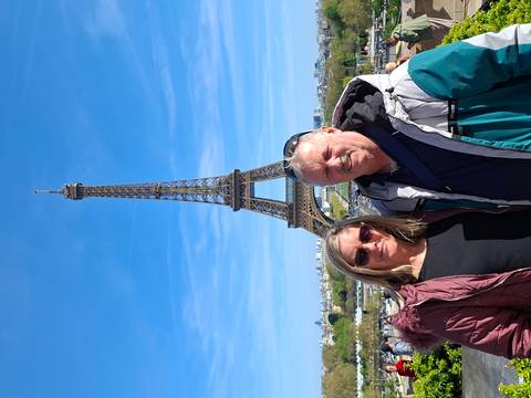       Couple posing in front of the Eiffel Tower on a bright blue-sky day in Paris.
  