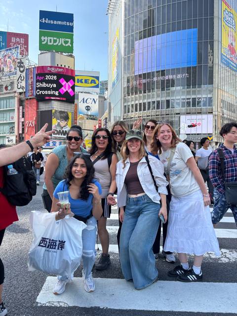       Friends smiling amid the crowds at Tokyo's bustling Shibuya Crossing.
  