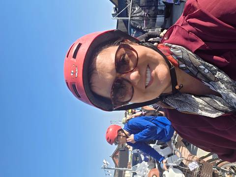       Woman taking a helmeted selfie under a clear blue sky during an outdoor tour.
  