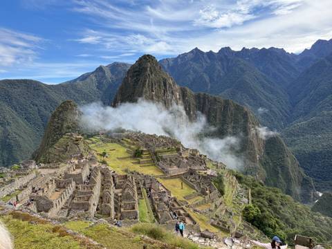       Iconic aerial view of Machu Picchu citadel with mist rising and dramatic Andean peaks behind.
  