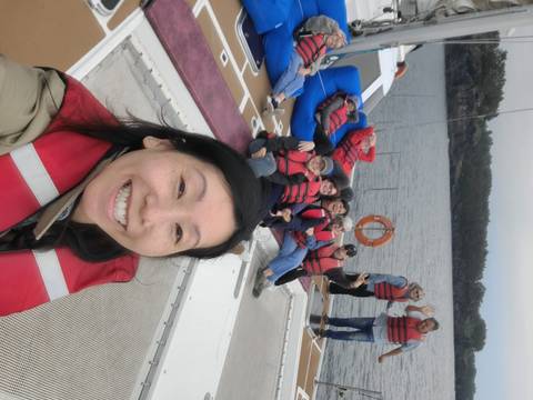       Traveler takes selfie with friends in red lifejackets relaxing on catamaran at sea.
  