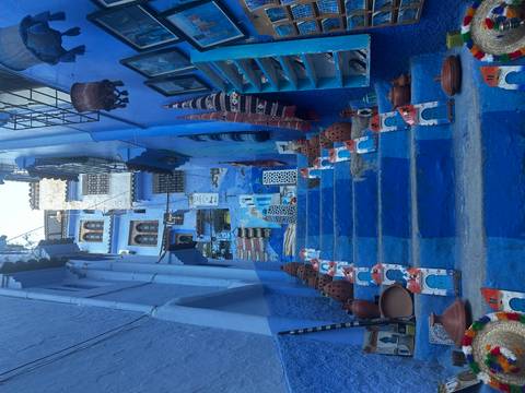       Steep blue staircase lined with handmade pottery and textiles in Chefchaouen.
  