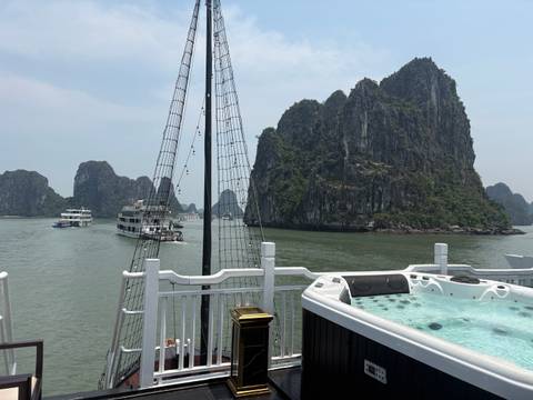       Cruise ships glide past towering limestone stacks while a jacuzzi deck overlooks the bay.
  
