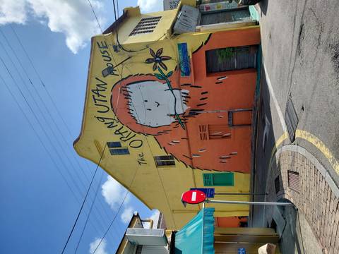       Bright yellow building with a playful 'Orang Utan House' mural on a sunny street corner in Malacca.
  