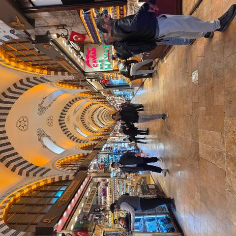       A bustling indoor bazaar with arched, ornate ceilings lit in warm tones; shoppers wander between colorful stalls.
  