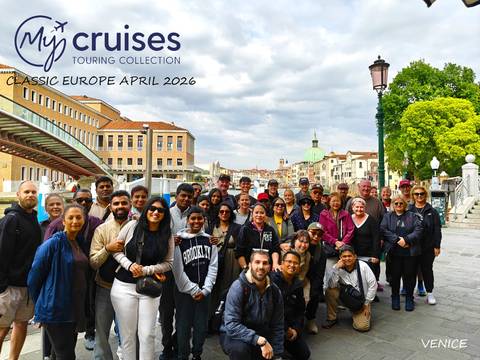       Large tour group photo on Venetian bridge with canal and dome behind.
  