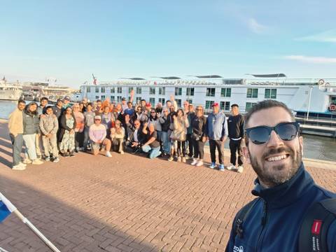       Selfie with large tour group and river cruise vessel in background.
  