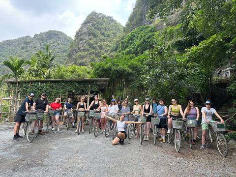       Cycling tour group poses with bicycles amid limestone karst scenery.
  