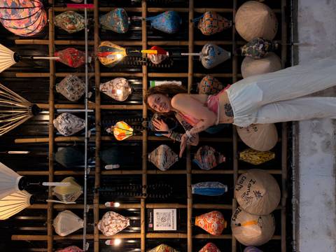       Woman posing playfully in front of a wall of ornate Vietnamese lanterns.
  