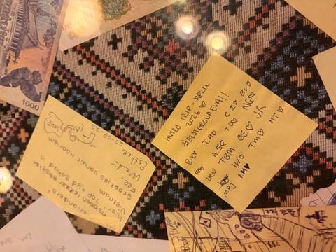       Close-up of handwritten sticky notes and currency on a patterned tablecloth.
  