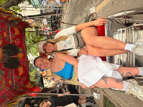       Two women seated in a traditional cycle rickshaw on a busy Hanoi street.
  