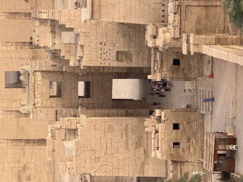       Group of tourists stands in a narrow temple doorway seen from above through multiple stone portals.
  