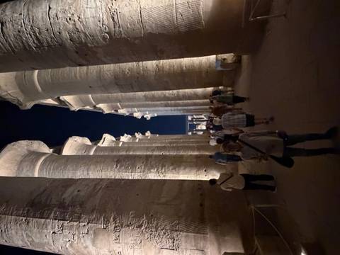      Nighttime walk through a colonnaded avenue of Luxor Temple illuminated by warm lights.
  