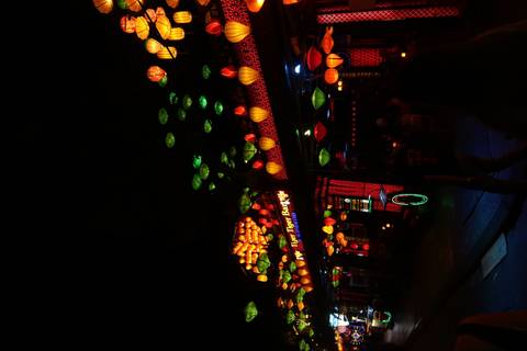       Night street in Hoi An glowing with multicolored silk lanterns and lively bar.
  