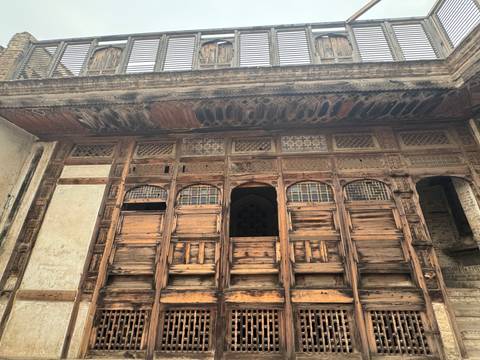       Intricately carved wooden façade of a historic merchant house with lattice windows.
  