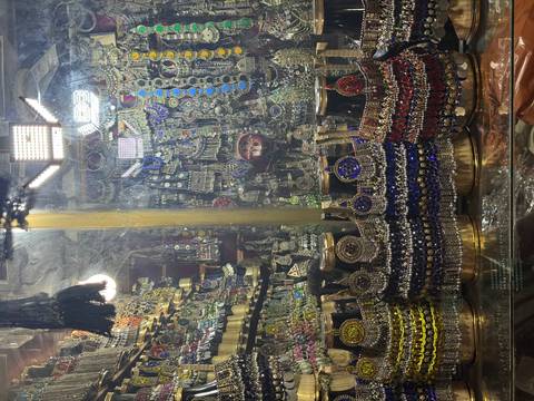       Colorful display of traditional Pakistani jewelry and trinkets sparkling under bright shop lights.
  