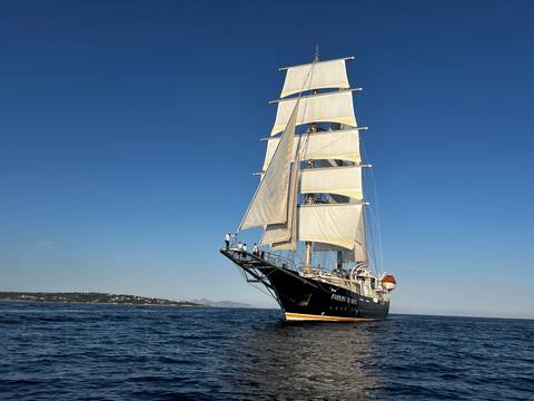      Side angle of elegant tall ship gliding over calm sea under blue sky
  