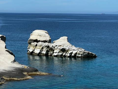       Isolated white rock formation rising from crystal blue sea
  