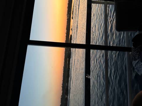       View through a cabin window of the Nile at dusk, with soft orange and blue twilight over the river.
  