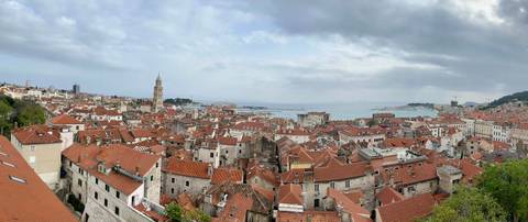       Panoramic skyline of Split, Croatia with red-tiled roofs, cathedral bell tower and Adriatic Sea beyond.
  