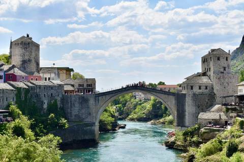       The iconic Stari Most stone bridge arches over a turquoise river framed by medieval towers.
  