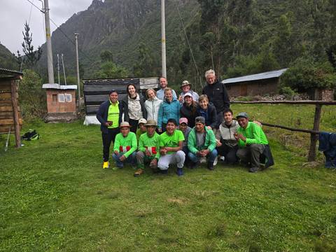       Trekkers and local crew pose together on a grassy clearing in the Andes after the hike.
  