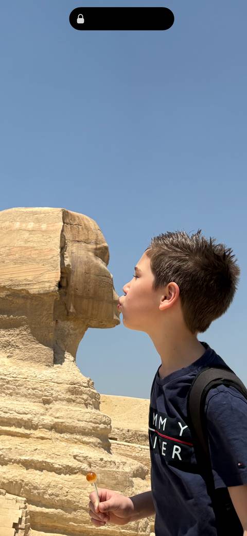       Boy playfully pretends to kiss the Great Sphinx of Giza in a classic perspective trick shot.
  