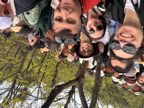       Crowded selfie with many tourists packed together on a wooded mountainside viewpoint.
  