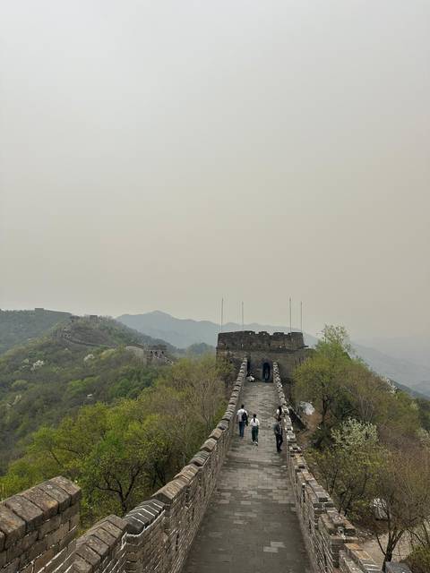       Section of the Great Wall stretching over misty hills under a hazy grey sky.
  