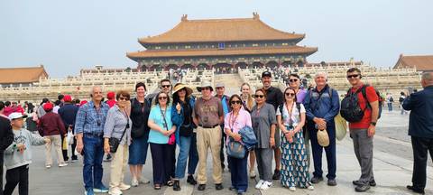       Group of tourists pose on the vast stone plaza before the grand Hall of Supreme Harmony in the Forbidden City.
  