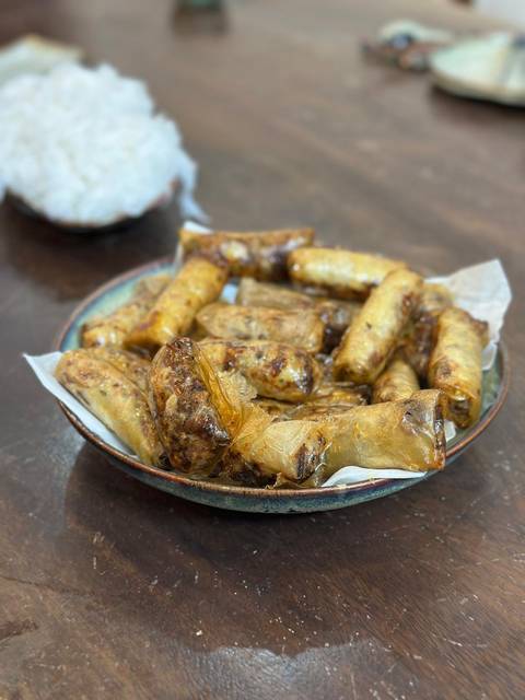       Plate piled high with freshly fried Vietnamese spring rolls on parchment paper.
  