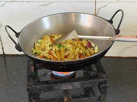       Stir-frying mixed vegetables in a metal wok over a blue gas flame on a stovetop.
  