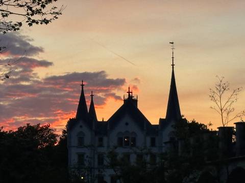       Silhouetted spires of a castle against a colorful sunset sky with streaks of clouds.
  