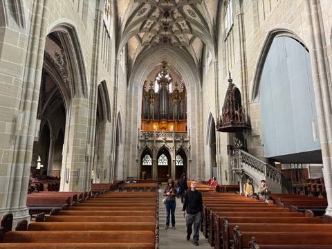       Grand gothic cathedral interior with soaring arches and ornate pipe organ above the nave.
  