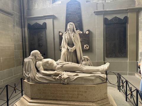       Marble sculpture of a recumbent figure with mourning woman in a historic church alcove.
  