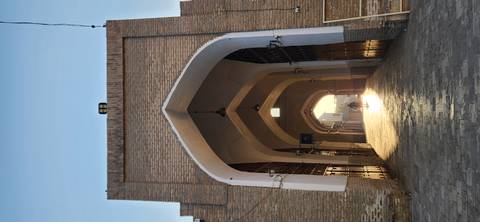       Long vaulted brick arcade glowing with early morning sunlight and lone figure in the distance.
  