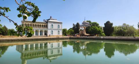      Elegant lakeside pavilion and palace reflected perfectly in calm water on a clear day.
  