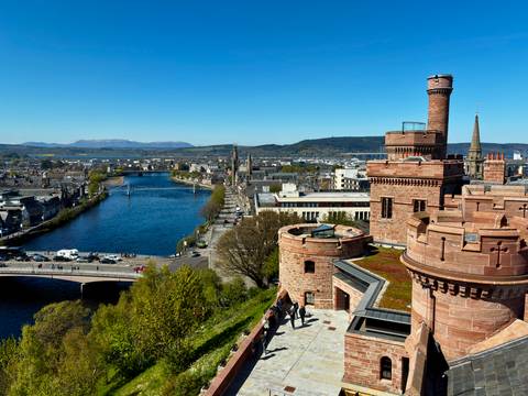       View from Inverness Castle overlooking the River Ness and distant Highlands under a clear blue sky.
  