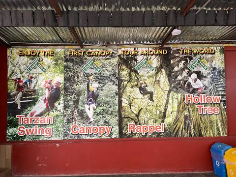       Advertising board with photos promoting canopy tours, tarzan swing and rappelling activities.
  