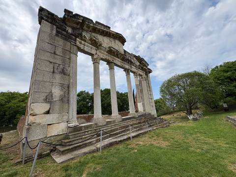       Classical stone columns and surviving wall fragments of Apollonia Archaeological Park under a cloudy sky.
  
